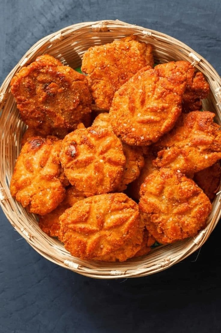 Homemade Chhath-style thekua in a bamboo basket, hand-pressed patterns